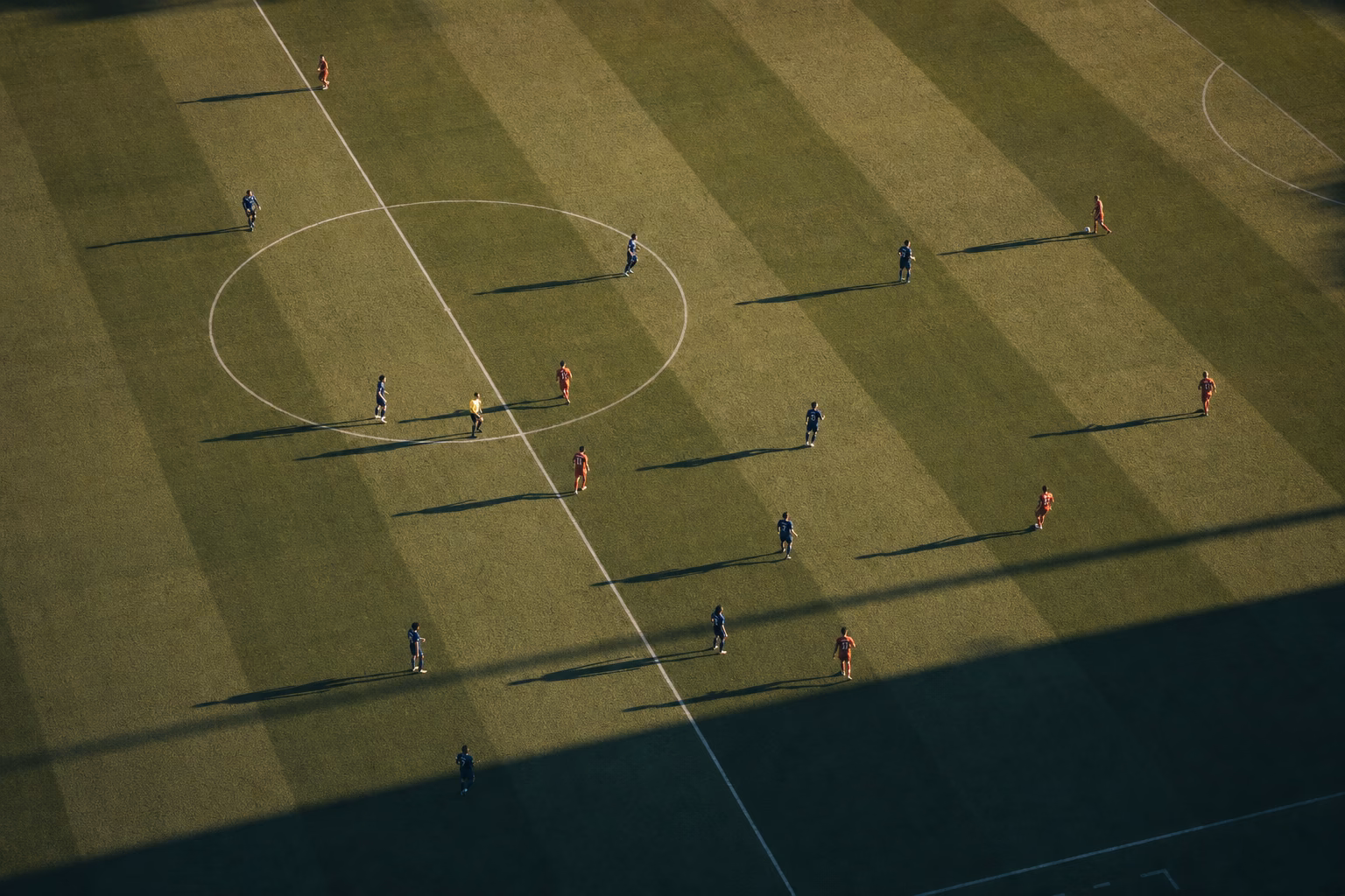 Vedere de sus asupra unui teren de fotbal cu jucătorii dispuși la mijloc